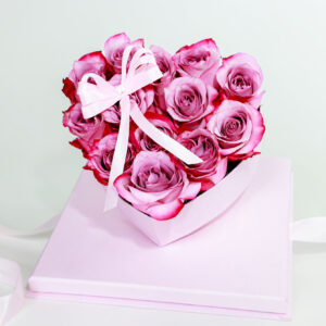 Arreglo floral en forma de corazón rosa con rosas frescas y lazo decorativo.