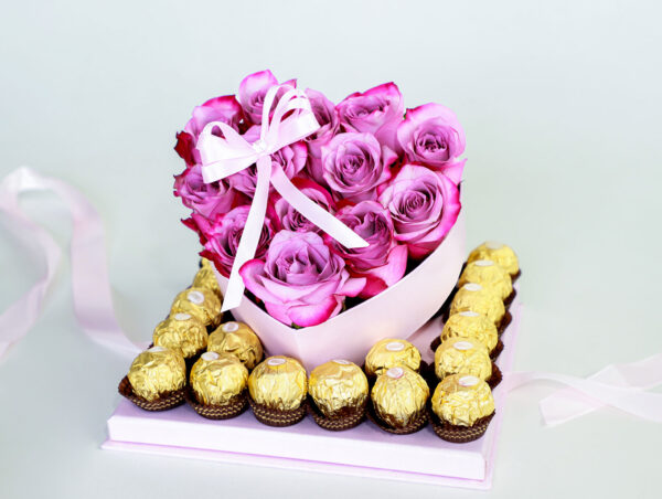 Arreglo floral en forma de corazón con rosas rosadas frescas y una caja de bombones Ferrero Rocher.