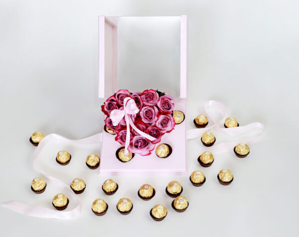 Arreglo floral en forma de corazón con rosas rosadas frescas y una caja de bombones Ferrero Rocher.