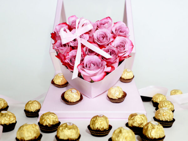 Arreglo floral en forma de corazón con rosas rosadas frescas y una caja de bombones Ferrero Rocher.