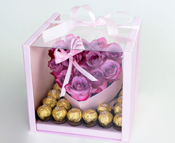 Arreglo floral en forma de corazón con rosas rosadas frescas y una caja de bombones Ferrero Rocher.