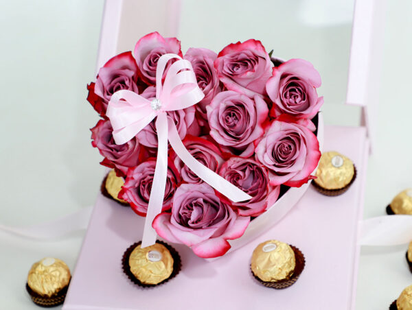 Arreglo floral en forma de corazón con rosas rosadas frescas y una caja de bombones Ferrero Rocher.