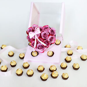 Arreglo floral en forma de corazón con rosas rosadas frescas y una caja de bombones Ferrero Rocher.