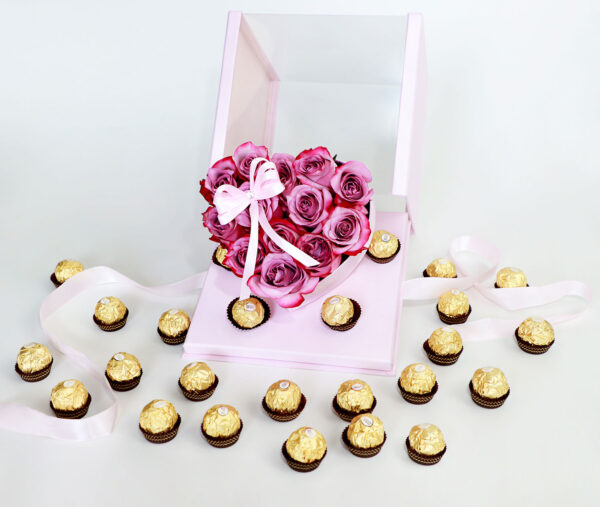 Arreglo floral en forma de corazón con rosas rosadas frescas y una caja de bombones Ferrero Rocher.