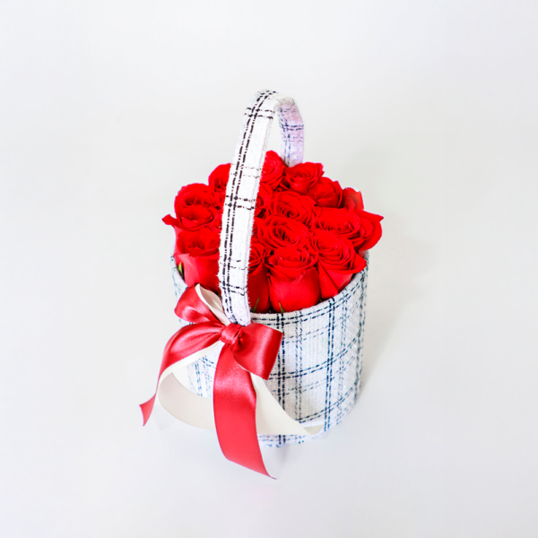 Arreglo floral de rosas rojas frescas en una canasta blanca con lazo rojo.