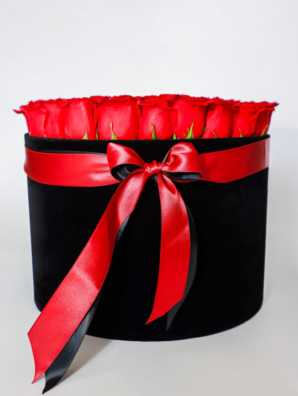 Arreglo floral de rosas rojas frescas en caja negra con lazo rojo decorativo.