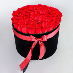 Arreglo floral de rosas rojas frescas en caja negra con lazo rojo decorativo.