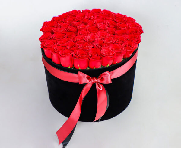 Arreglo floral de rosas rojas frescas en caja negra con lazo rojo decorativo.